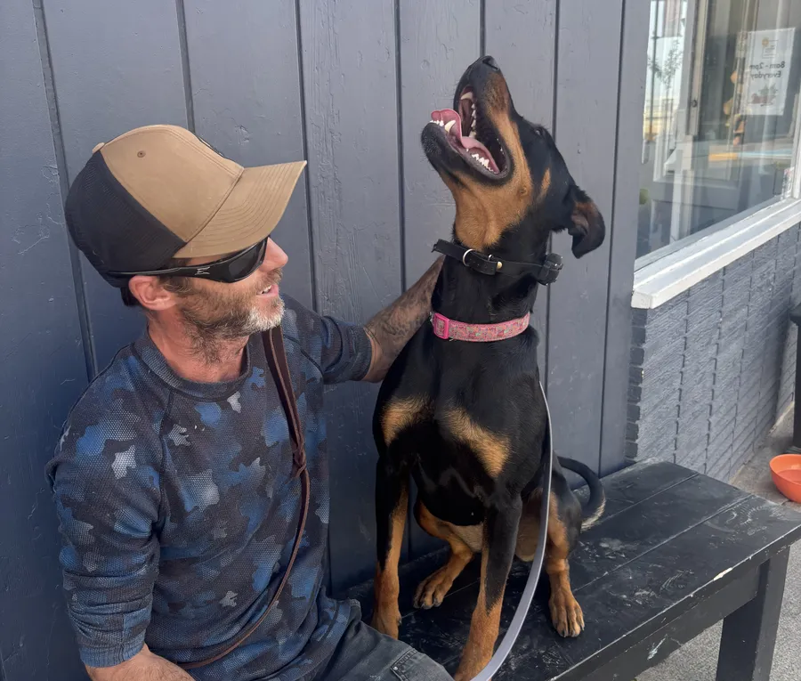 Tyler sitting on a bench with a happy black and tan dog looking up at him